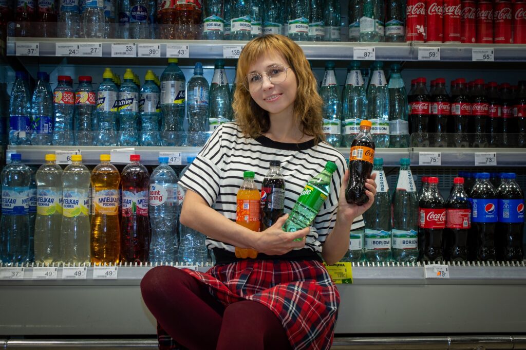 a lady holding carbonated drinks in a supermarket